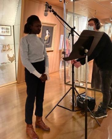 Une jeune fille enregistre devant un micro face à l'oeuvre sa lecture du texte en audiodescription